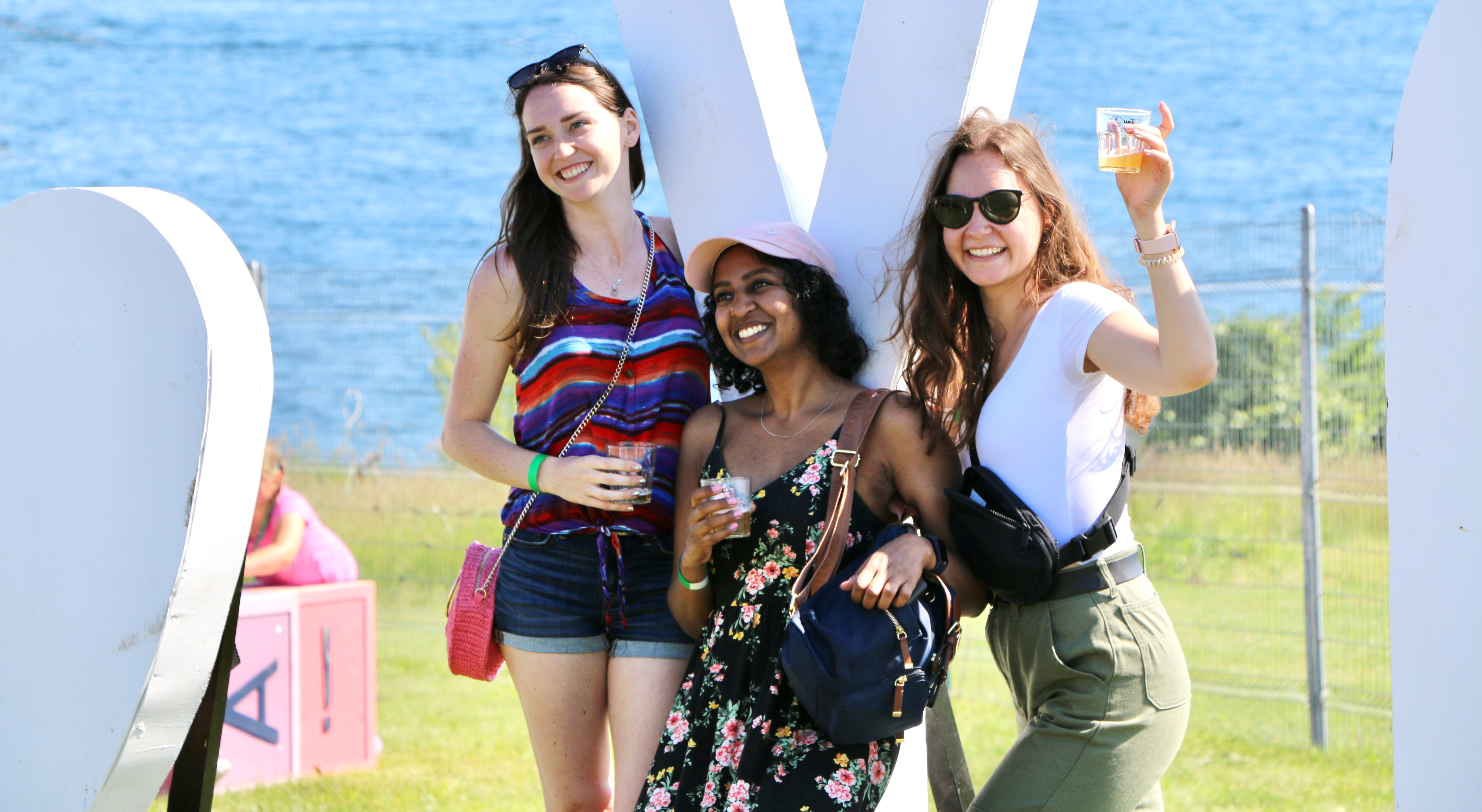 Three female posing for photo while holding beer filled glasses.